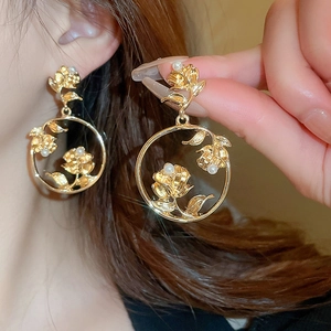 Detailed view of vintage gold rose earrings with pearls worn by a model