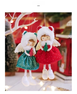 Close-up of plush red and green Christmas angel dolls with gold wings on white branches