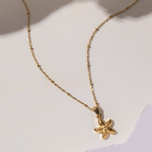 Close-up of golden beaded chain necklace featuring a textured starfish pendant design
