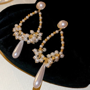 Detailed view of elegant gold drop earrings with white pearls in a black heart jewelry box