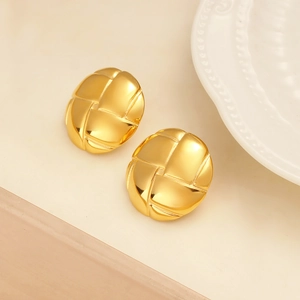 Detailed close-up of golden oval earrings featuring an intricate woven texture design