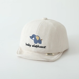 Close-up of soft beige baby cap featuring blue elephant embroidery and brand label detail