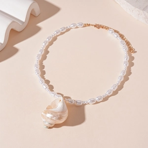 Macro shot of white pearl beaded necklace with a natural conch pendant and gold clasp