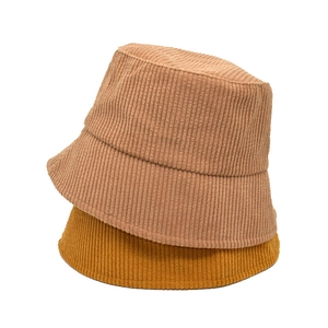 Close-up of stacked beige and yellow corduroy bucket hats with vertical stripe texture