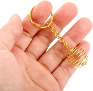 Detailed view of a golden metal lantern cage spiral pendant held by hand on white background