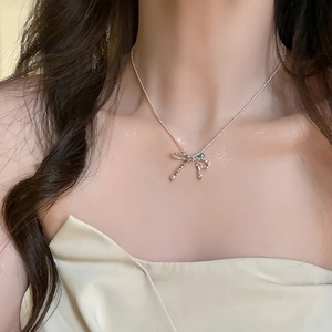 Close-up of silver bow pendant necklace with pearl detail on a female model neck