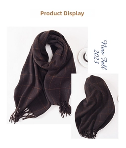 Detailed view of thick winter scarf with orange grid patterns and tassel fringe edge