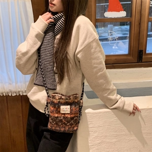 Detail view of a vintage plush knit crossbody bag with a colorful branded label and scarf