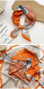 Detailed close-up of orange silk scarf featuring horse and geometric patterns on fabric