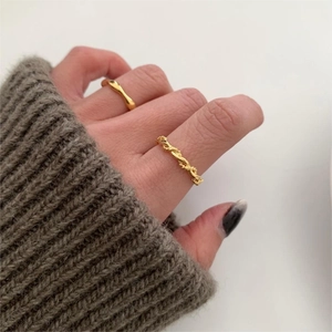Detail of 925 sterling silver twisted rings in gold finish worn with knitwear