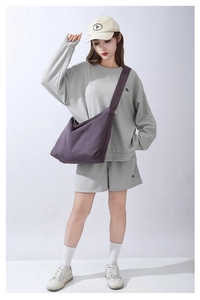 Dettaglio di una borsa a tracolla in tela viola capiente indossata con stile casual