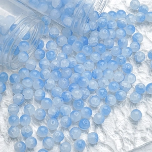 Macro shot of 10mm blue ice-cracked glass beads spilling from glass tubes for DIY jewelry