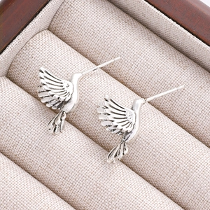 Macro shot of vintage silver hummingbird stud earrings with detailed feather texture