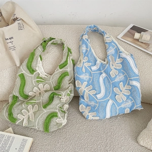 Detail of floral lace embroidery and tassel edges on canvas underarm tote bags