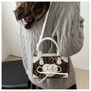 Detail of leopard print handbag with heart leather patch and bow on a textured sweater