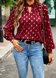 Detail of burgundy long sleeve blouse with gold metallic polka dots and neck tie design