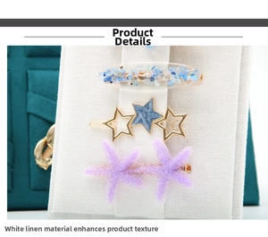 Macro shot of hair clips featuring blue stones, gold stars, and purple starfish on linen card