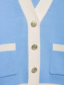 Detalle de cárdigan de punto en contraste con botones dorados grabados y cuello en V