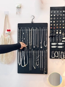 Detail of black felt wall hanging jewelry organizer with hooks for necklaces and bracelets