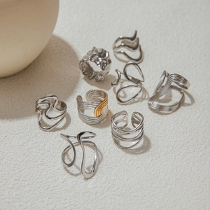 Artistic display of geometric and lava texture mixed metal rings on a beige background