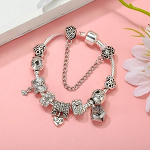 Detail of silver snake chain bracelet with heart charms and bow pendant on pink floral tray
