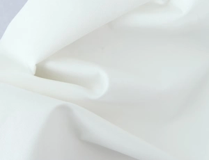 Detailed close-up showing the fine texture and drape of the white fabric on this dress