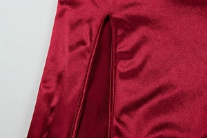 Detail of burgundy satin dress showing a high side slit and smooth fabric texture