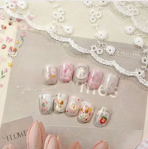 Detailed view of pink and cream press-on nails with 3D cartoon rabbits and floral motifs