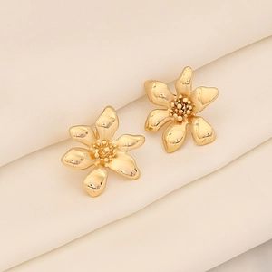 Detailaufnahme goldener Sonnenblumen-Ohrstecker auf elegantem weißem Plissee-Seidenstoff