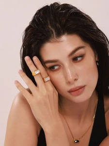Dettaglio di anelli placcati oro 18k con inserti in conchiglia sulla mano della modella