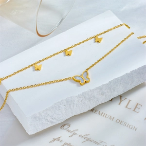 Golden butterfly layered anklet with shell inlay on minimalist white stone display