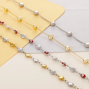 Detail of gold and silver heart-shaped chains with evil eye beads on two-tone background