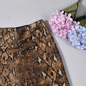 Detailansicht eines Rocks mit Schlangenmuster, schimmernden Pailletten und Textur