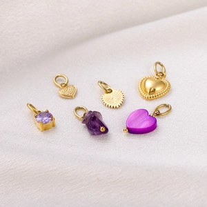 Detailed view of six gold-plated heart and geometric pendants with purple stones