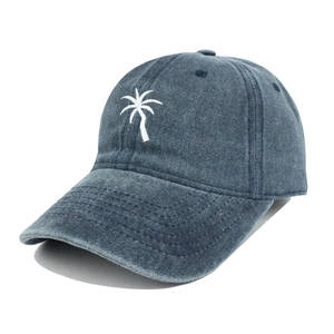 Close-up of white coconut tree embroidery on blue-grey washed cotton baseball cap