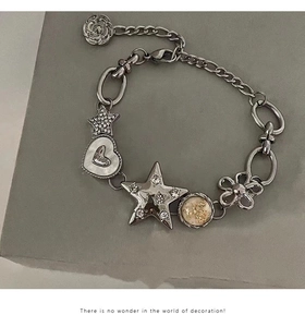 Detail view of silver metal bracelet with rhinestone star, heart and shell pendants