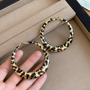 Detailed view of large leopard print hoop earrings with gold finish on a jewelry tray