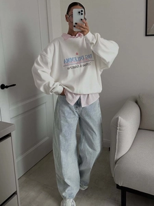 Oversize white crewneck sweatshirt with pink shirt and blue wide-leg jeans