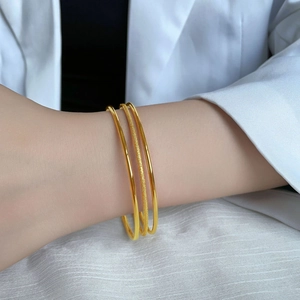 Three-piece gold plated bangle set with polished and frosted finish on a female wrist