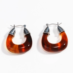 Dettaglio degli orecchini a U in resina ambrata con fibbie geometriche in argento