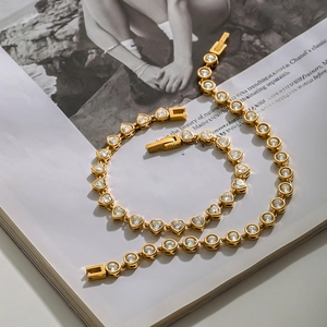 Close-up of gold stainless steel bracelets with heart and round cubic zirconia on a magazine