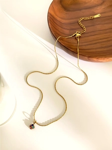 Detail of a gold necklace featuring a floral pendant set with colorful vibrant crystals