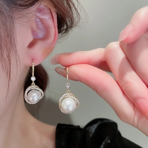 Gros plan d'élégantes boucles d'oreilles perles dorées serties de diamants sur un mannequin