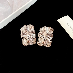 Detail of champagne gold square earrings with irregular wrinkled texture on black velvet