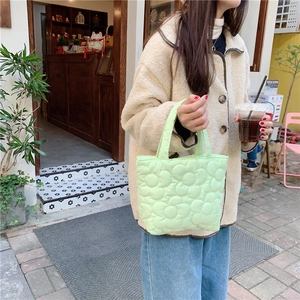 Close-up of mint green quilted tote bag featuring floral embroidery and soft padding