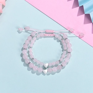 Detail of pink zebra stone beaded bracelets with heart pendants on a pastel background