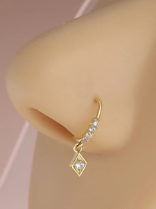 Macro detail of gold nose hoop with white zircons and diamond-set rhombus pendant