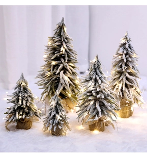 Detailed close-up of mini flocked Christmas trees with LED lights and burlap base
