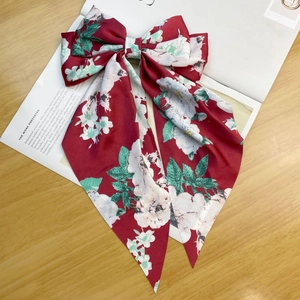 Detail of red floral satin ribbon bow hair clip with camellia pattern on an open book
