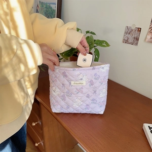 Detail of lavender quilted makeup bag featuring floral teddy bear pattern and woven label